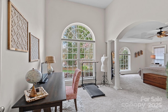 office space featuring arched walkways, carpet floors, decorative columns, a wealth of natural light, and a ceiling fan