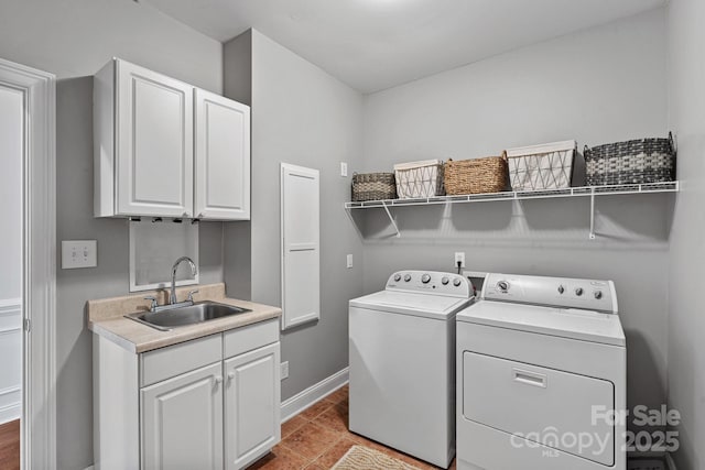 washroom with cabinet space, a sink, independent washer and dryer, and baseboards