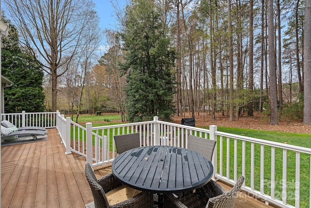 wooden deck featuring a lawn and outdoor dining area