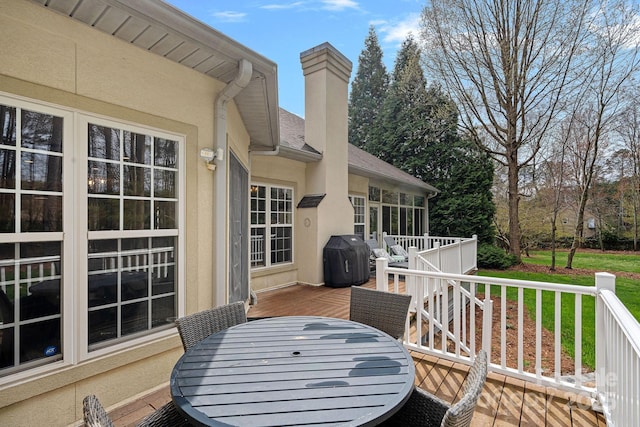 wooden terrace with outdoor dining area, grilling area, and a yard
