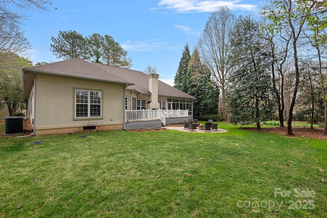 back of house featuring a chimney, stucco siding, a patio area, central AC, and a lawn