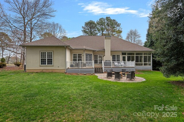 back of house with a wooden deck, a patio area, stucco siding, a lawn, and a sunroom
