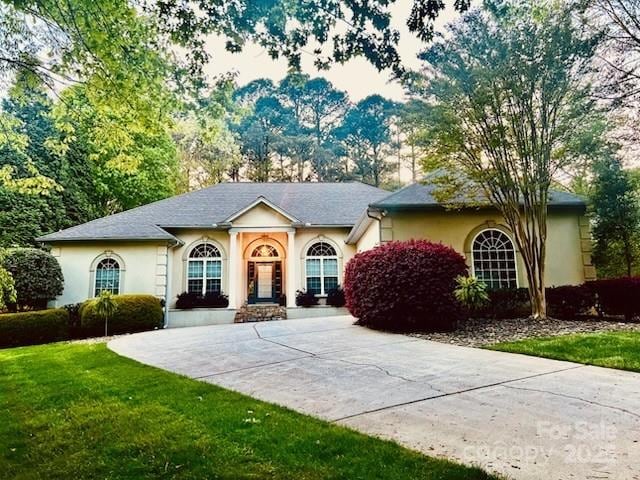 view of front of house with a front lawn, stucco siding, and concrete driveway