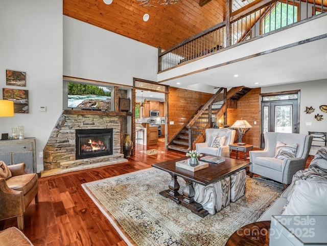 556 High Pines Loop, Lake Lure, NC 28746 - living room featuring a high ceiling, stairway, a stone fireplace, wood finished floors, and wooden walls