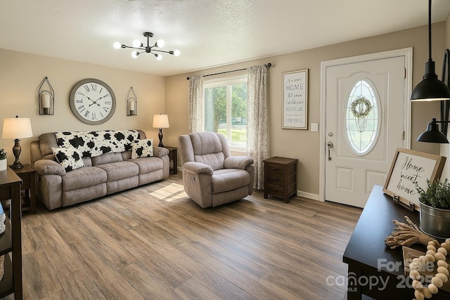 living area featuring wood finished floors, baseboards, and a notable chandelier