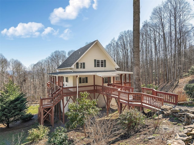 back of house featuring roof with shingles, stairs, and a wooden deck