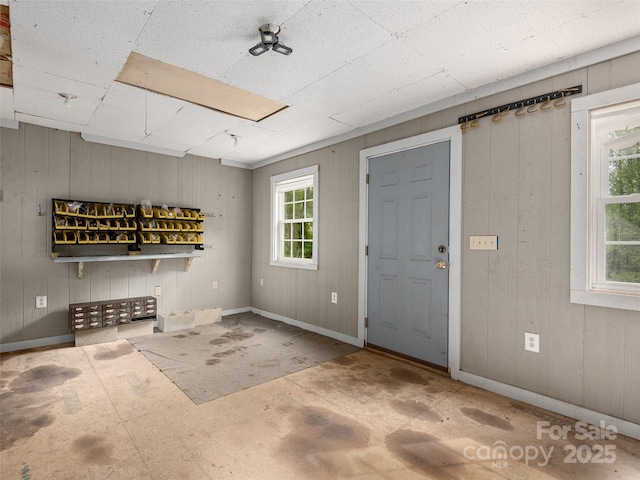 foyer with a healthy amount of sunlight, baseboards, and wood walls