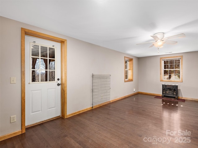 575 Twin Brook Dr, Waynesville, NC 28785 - unfurnished living room featuring a wood stove, dark wood-type flooring, baseboards, ceiling fan, and healthy amount of natural light