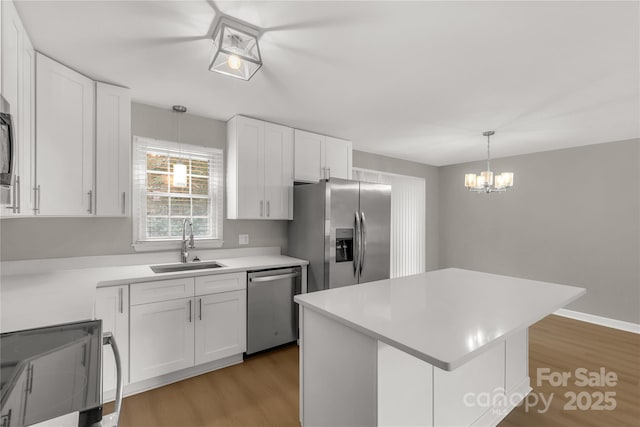 kitchen with white cabinets, appliances with stainless steel finishes, a sink, and light wood-type flooring