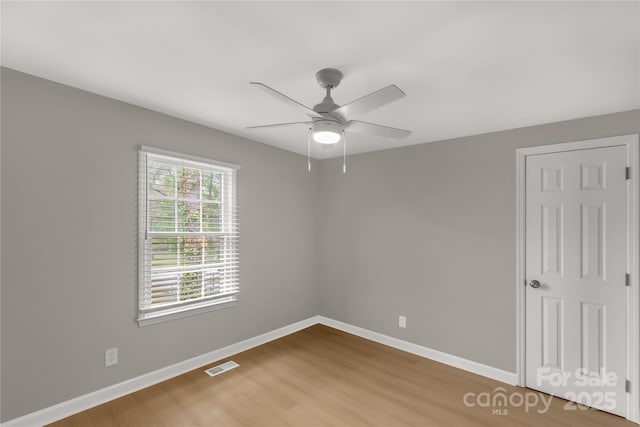 spare room with visible vents, ceiling fan, wood finished floors, and baseboards
