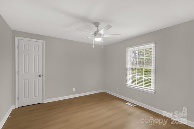 unfurnished room featuring ceiling fan, visible vents, baseboards, and wood finished floors