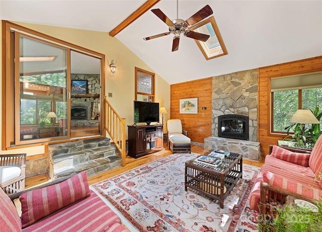 1192 Rockdale Rd, Whittier, NC 28789 - living area with wood finished floors, a fireplace, wooden walls, vaulted ceiling with skylight, and a ceiling fan