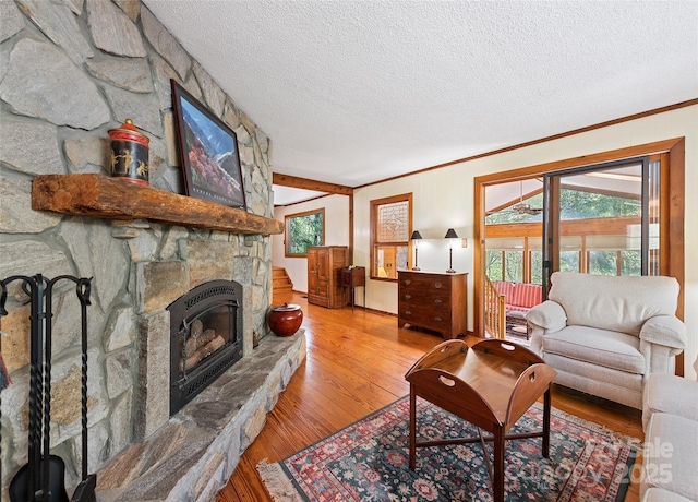 1192 Rockdale Rd, Whittier, NC 28789 - living room featuring a stone fireplace, ornamental molding, a textured ceiling, and wood finished floors
