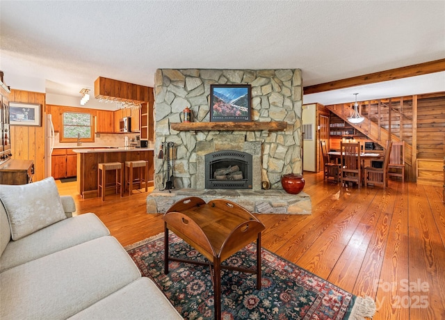 1192 Rockdale Rd, Whittier, NC 28789 - living area featuring a stone fireplace, a textured ceiling, light wood-style flooring, and wooden walls