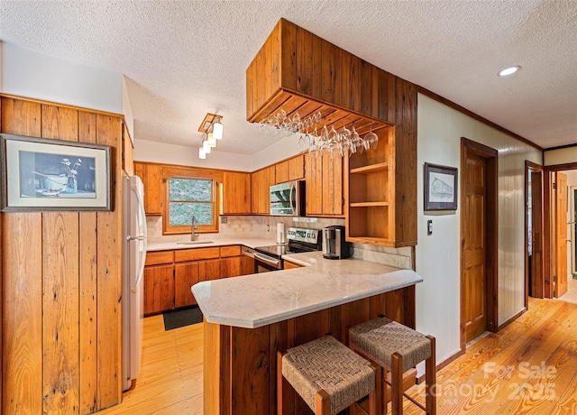1192 Rockdale Rd, Whittier, NC 28789 - kitchen with appliances with stainless steel finishes, a sink, a textured ceiling, light wood-style flooring, and a peninsula