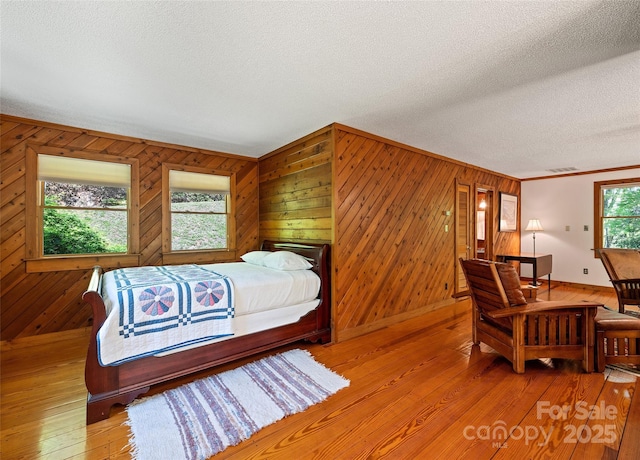 1192 Rockdale Rd, Whittier, NC 28789 - bedroom featuring visible vents, wood walls, ornamental molding, light wood-type flooring, and a textured ceiling