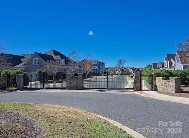 view of street featuring curbs, a gate, a residential view, a gated entry, and sidewalks
