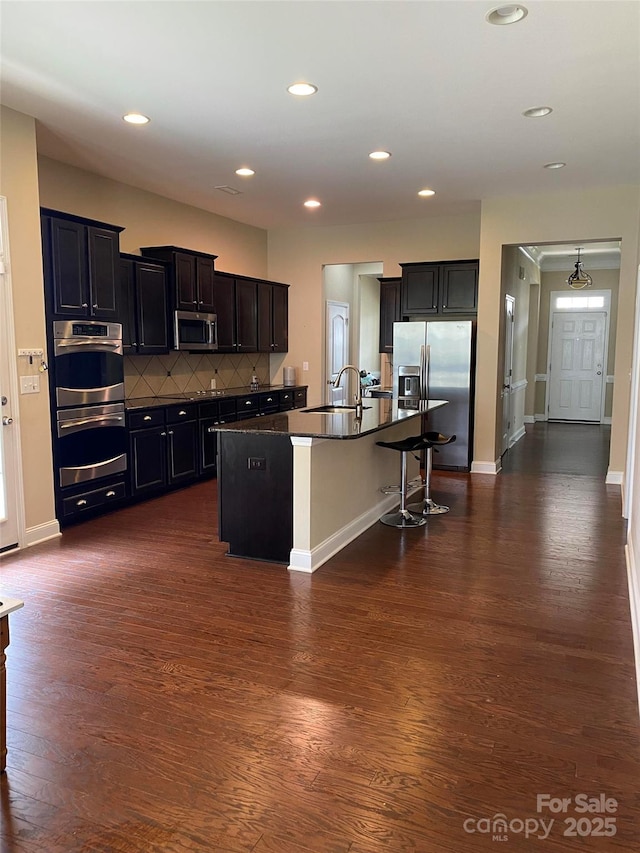 kitchen featuring dark countertops, baseboards, appliances with stainless steel finishes, and dark wood-style floors