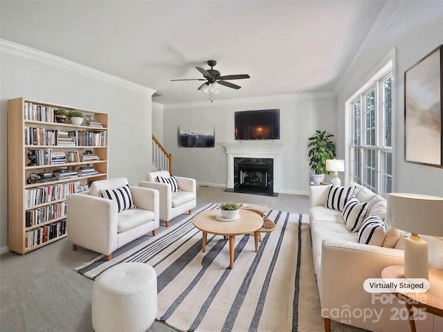 carpeted living area with stairs, crown molding, a premium fireplace, baseboards, and ceiling fan