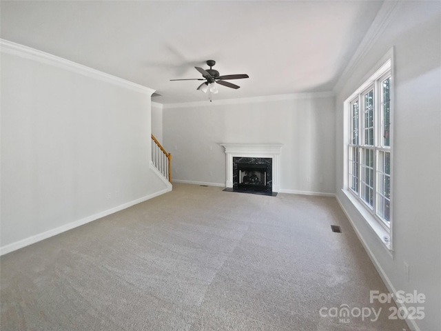 unfurnished living room with crown molding, ceiling fan, carpet, and a premium fireplace