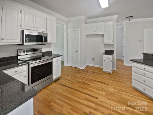 kitchen with white cabinets, baseboards, ornamental molding, stainless steel appliances, and light wood-style floors