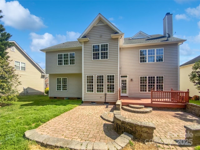 rear view of property featuring a patio, crawl space, a deck, a yard, and a chimney