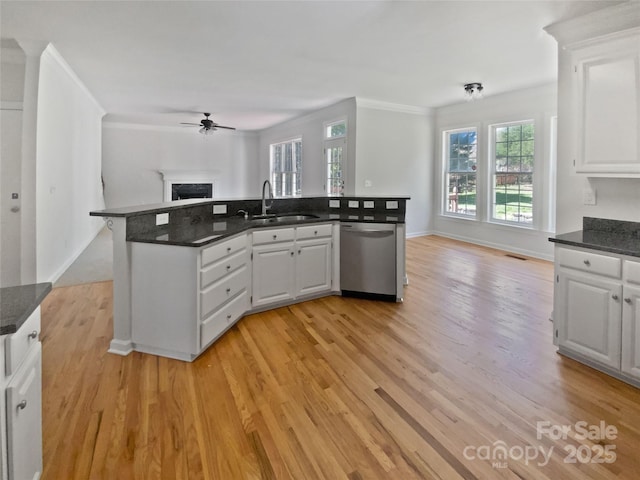 kitchen with open floor plan, a sink, dishwasher, a ceiling fan, and a fireplace