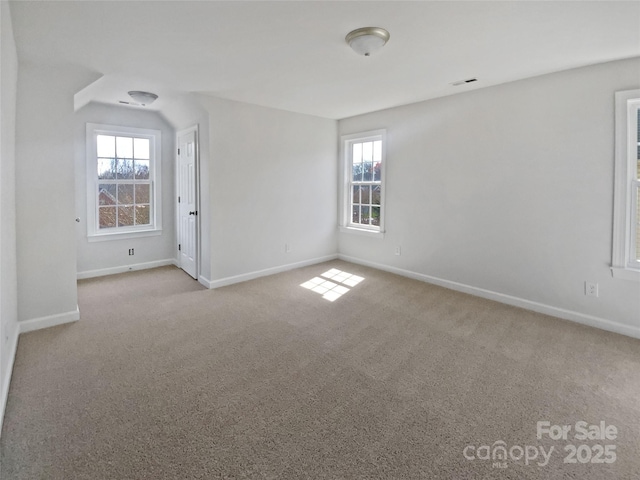 carpeted spare room with baseboards, a healthy amount of sunlight, and visible vents