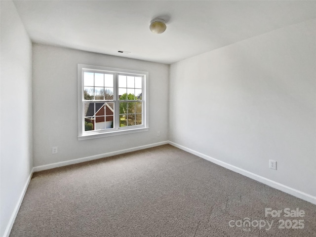 spare room featuring baseboards, visible vents, and carpet