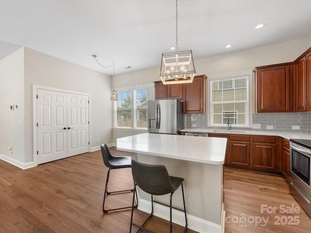 4148 Cedar Point Ave, Matthews, NC 28104 - kitchen featuring stainless steel appliances, a breakfast bar, backsplash, wood finished floors, and recessed lighting