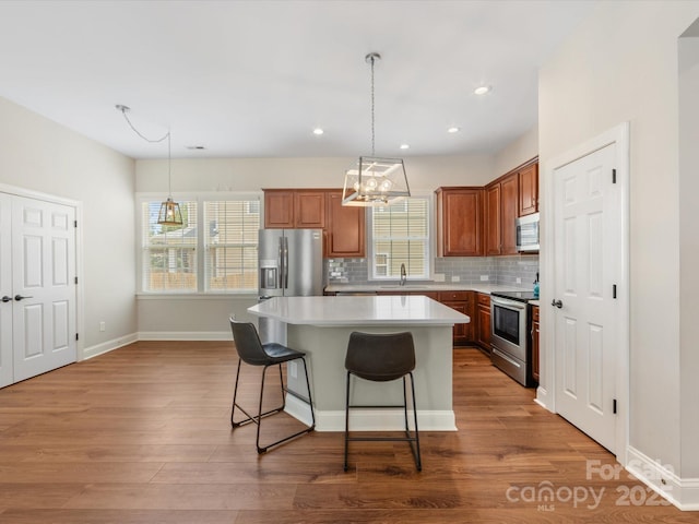 4148 Cedar Point Ave, Matthews, NC 28104 - kitchen featuring stainless steel appliances, a center island, a kitchen bar, decorative backsplash, and brown cabinetry