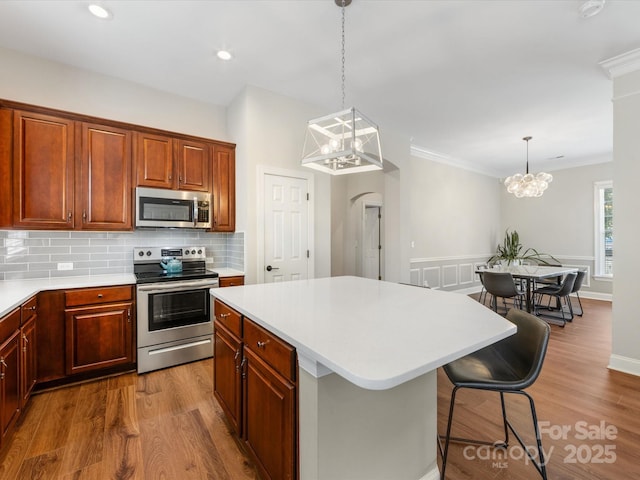 4148 Cedar Point Ave, Matthews, NC 28104 - kitchen with appliances with stainless steel finishes, a chandelier, light countertops, a kitchen island, and ornamental molding