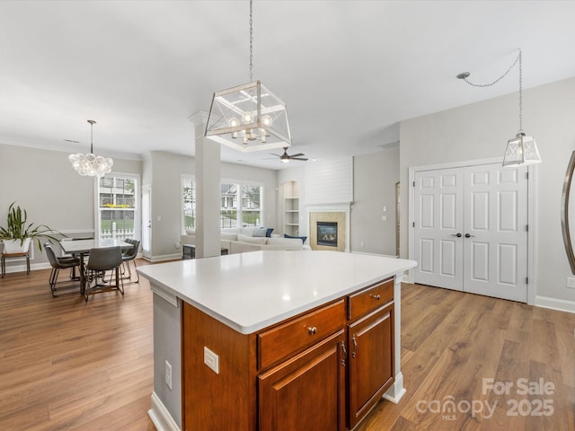 4148 Cedar Point Ave, Matthews, NC 28104 - kitchen featuring a chandelier, a glass covered fireplace, light countertops, wood finished floors, and ceiling fan