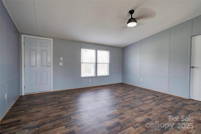unfurnished room with a decorative wall, a ceiling fan, and wood finished floors