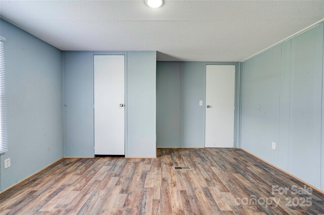 empty room featuring wood finished floors, a textured ceiling, and visible vents