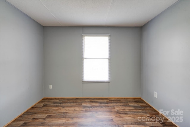 unfurnished room featuring a wealth of natural light, a textured ceiling, and wood finished floors