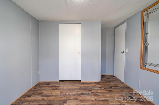 unfurnished bedroom with a textured ceiling and wood finished floors