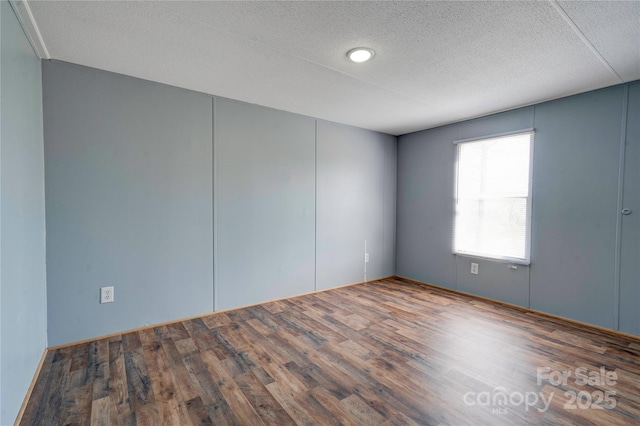unfurnished room with wood finished floors and a textured ceiling