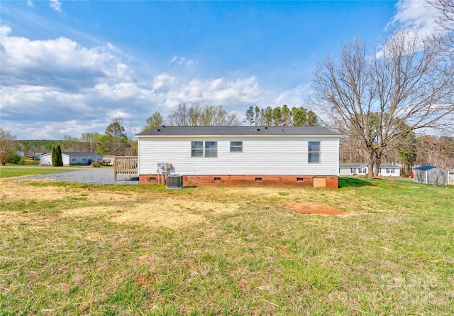 rear view of house with central AC, crawl space, and a yard
