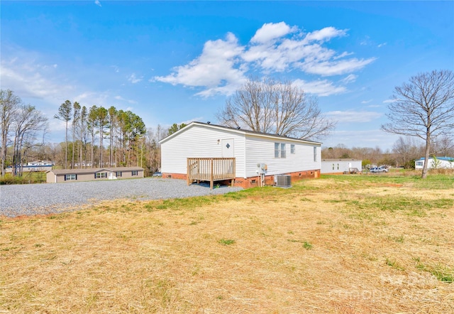rear view of house featuring crawl space, cooling unit, a wooden deck, and a yard