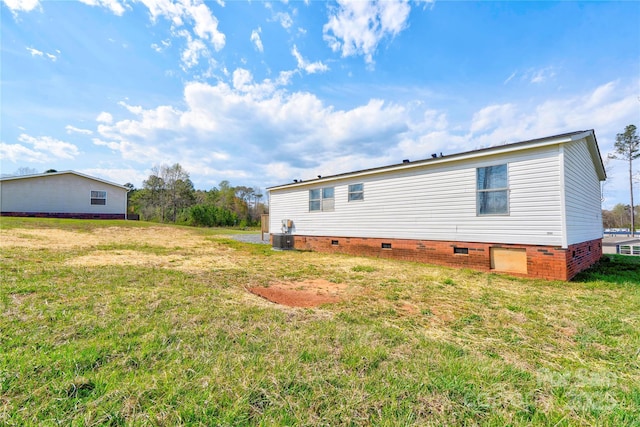 rear view of house featuring central air condition unit, crawl space, and a yard