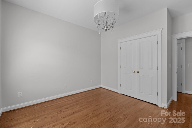 9652 Alma Blount Blvd, Charlotte, NC 28277 - unfurnished bedroom featuring wood finished floors, a closet, baseboards, and a notable chandelier