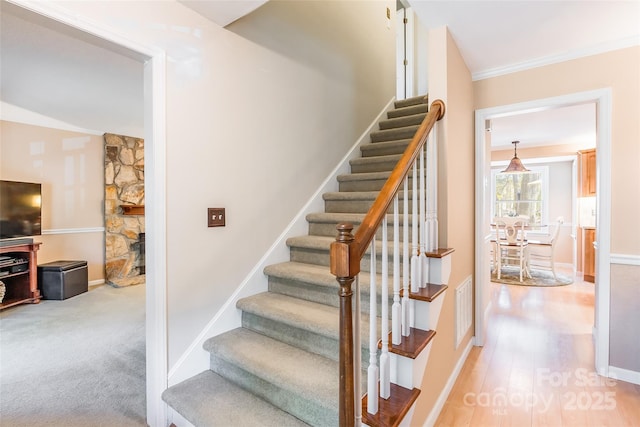 10028 Bora Bora Dr, Tega Cay, SC 29708 - stairs featuring crown molding, a stone fireplace, baseboards, visible vents, and carpet