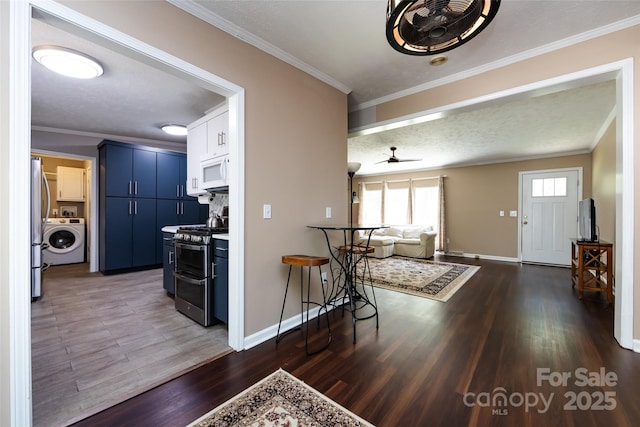 interior space with stainless steel appliances, washer / clothes dryer, blue cabinets, and crown molding