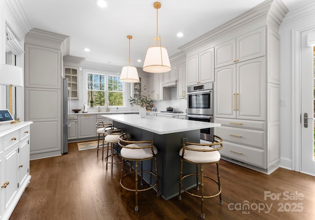 kitchen featuring dark wood-type flooring, appliances with stainless steel finishes, a kitchen island, and a kitchen breakfast bar