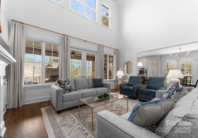 living room featuring an inviting chandelier, a high ceiling, a wealth of natural light, and wood finished floors