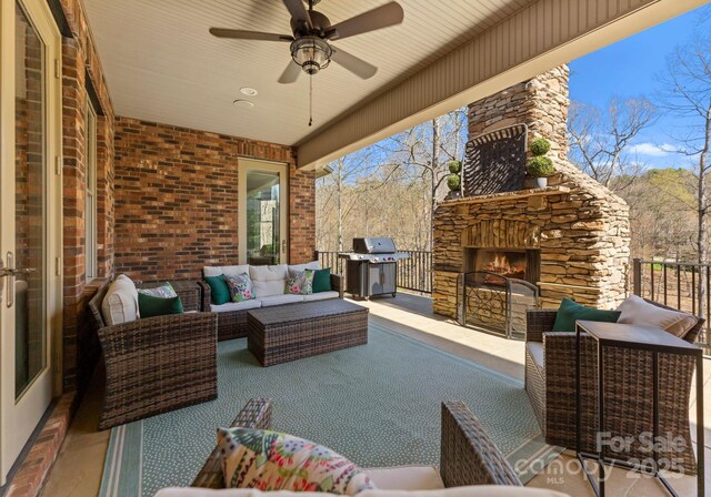 view of patio with an outdoor living space with a fireplace and a grill