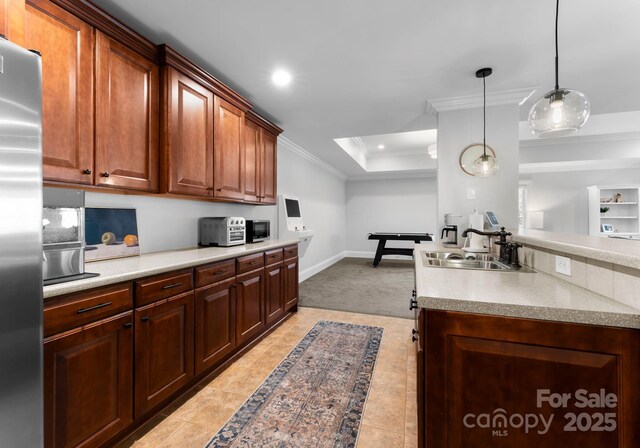 kitchen featuring light tile patterned flooring, stainless steel fridge, a sink, light countertops, and ornamental molding