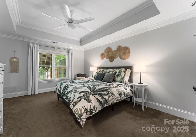 bedroom featuring a tray ceiling, visible vents, ornamental molding, and dark colored carpet