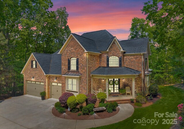 traditional-style home with french doors, concrete driveway, roof with shingles, and brick siding